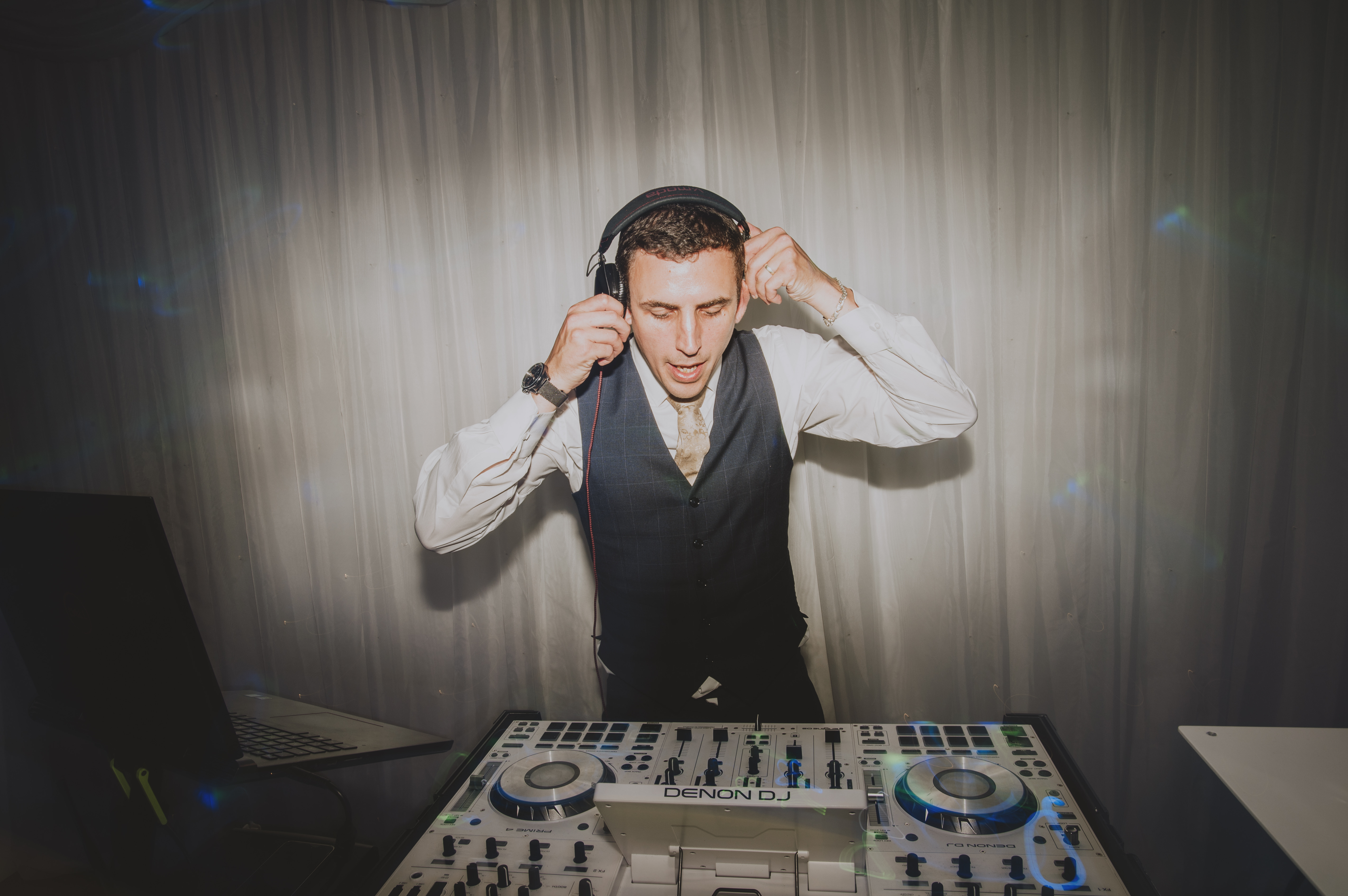 DJ Dan performing at a wedding with his signature all-white DJ setup, including premium sound and lighting equipment.